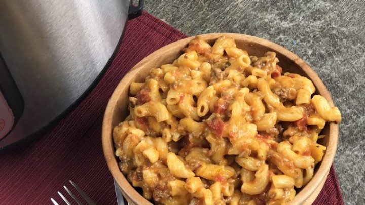 top view of cheesy goulash in a wooden bowl with 2 forks next to instant pot