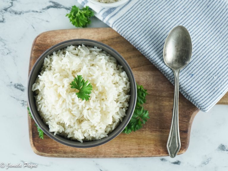 Top view of instant pot rice in a gray bowl with a spoon next to it on a brown cutting board with gray paper towel