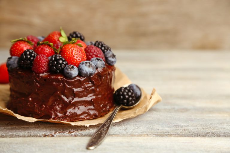 Tasty chocolate cake with different berries on wooden table