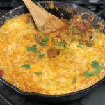 cheesy taco skillet with wooden spoon sticking out of a skillet