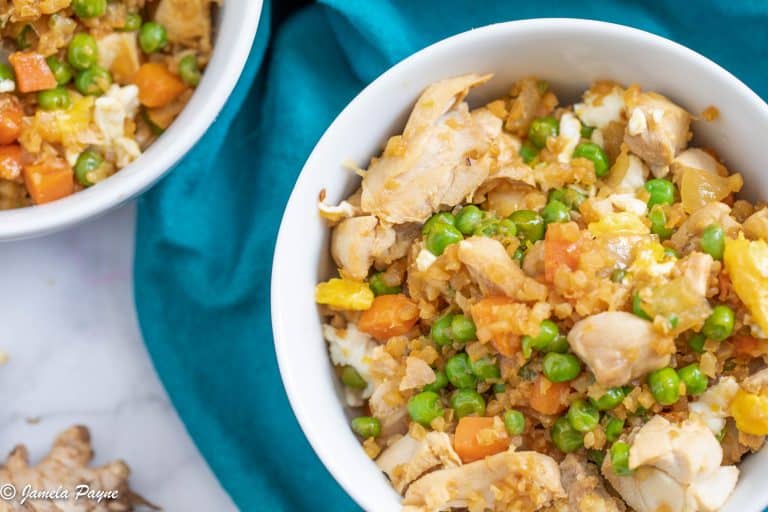 close up top view of chicken fried cauliflower rice on a teal napkin and a white bowl