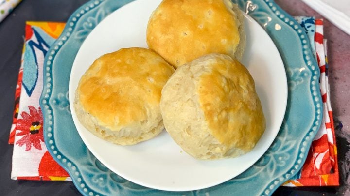3 Air fryer biscuits on stacked plates with a floral cloth napkin underneath
