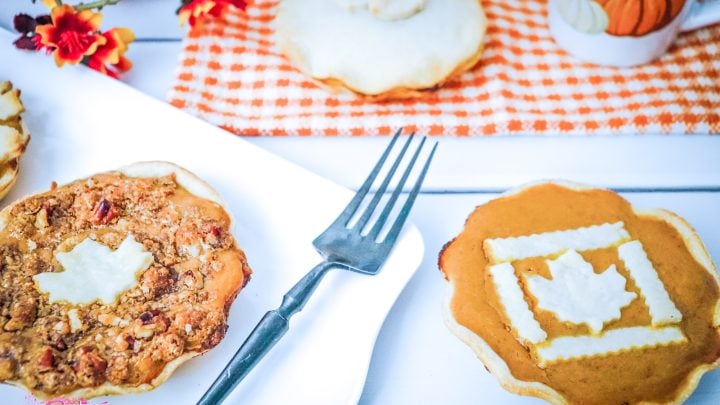pumpkin pies with fall leaf decor on top on orange and white plaid table napkin and plate