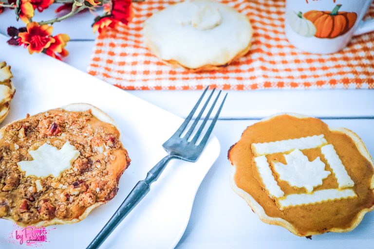 pumpkin pies with fall leaf decor on top on orange and white plaid table napkin and plate