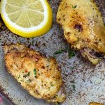 top close up of lemon pepper wins made in the air fryer, on a baking sheet with lemon slices