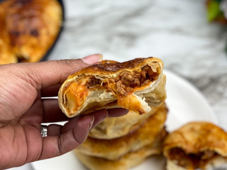 sloppy joe cut in half with ground beef and mozzarella cheese on the inside with more sloppy joes in background
