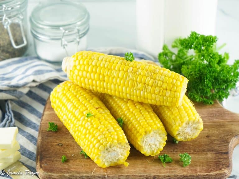 close up of Instant pot corn on the cob stacked brown cutting board and on a gray and white striped towel